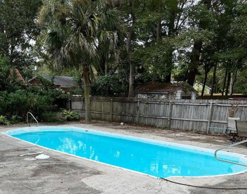 ein blauer Pool in einem Garten mit einem Zaun in der Unterkunft Charming home near Folly & Downtown Charleston in Charleston