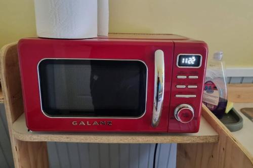 a red microwave sitting on top of a shelf at cozy apartment near the ocean in Guysborough