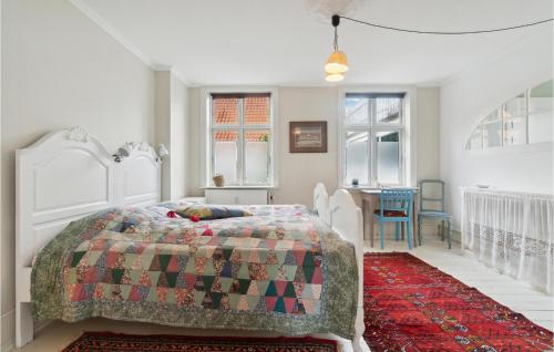 Schlafzimmer mit einem Bett, einem Tisch und Fenstern in der Unterkunft Lovely Apartment In Svaneke With House Sea View in Svaneke