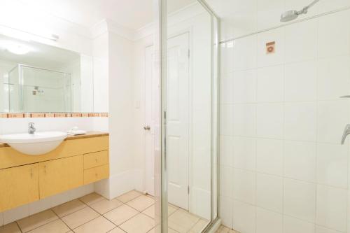 La salle de bains est pourvue d'une douche en verre et d'un lavabo. dans l'établissement 27 Central Plaza, à Port Douglas