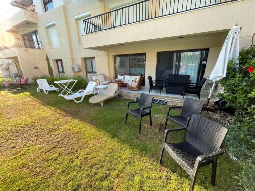 a yard with chairs and tables and a building at Ground chlat first row lagoon 2 bedrooms at Blanca marassi in El Alamein