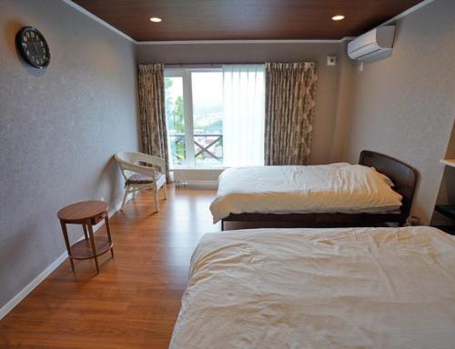 um quarto de hotel com duas camas e uma janela em 民泊森の家 em Moiwashita