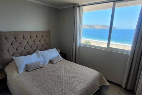 a bedroom with a bed with a view of the beach at Apartamento La Herradura, primera línea. in Coquimbo