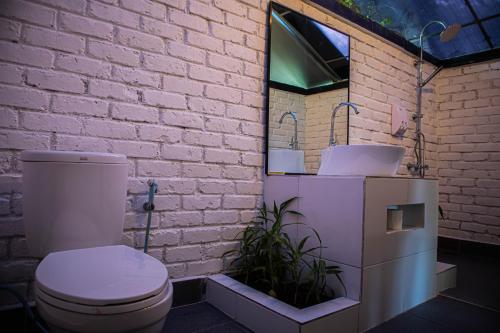 La salle de bains est pourvue de toilettes et d'un mur en briques blanches. dans l'établissement "D'BAMBOO KAMP" Desa Wisata Ekang, à Lagoi