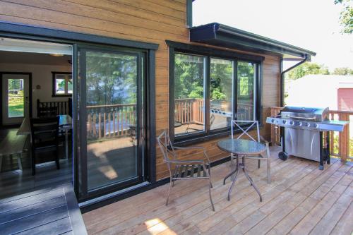 eine abgeschirmte Veranda mit einem Grill sowie einem Tisch und Stühlen in der Unterkunft Magnifique chalet au bord du Lac-Saint-Jean in Roberval