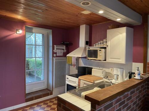 une cuisine avec un évier, une cuisinière et une fenêtre dans l'établissement Fermette au calme avec jardin clos, proche station thermale, animaux acceptés et nombreuses commodités - FR-1-489-244, à Hyds
