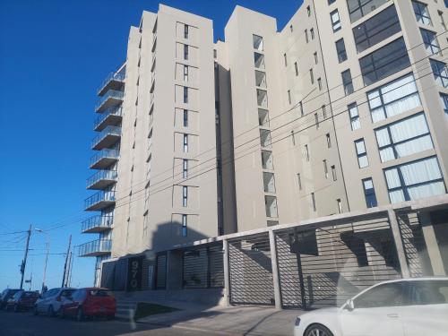 a white car parked in front of a tall building at Marmol y Constitución, con vista al mar in Mar del Plata