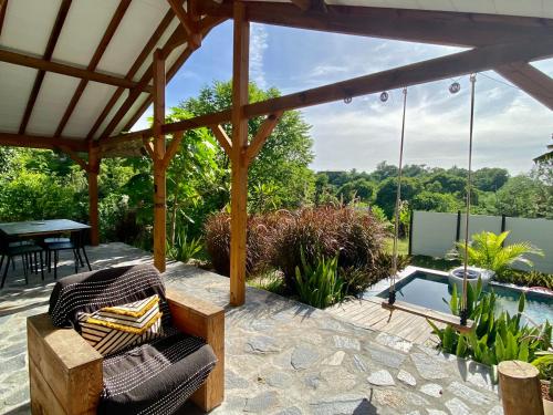 a patio with a pergola with a table and a pool at Villa Kara in Grand-Bourg