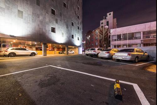 a parking lot with parked cars in a city at night at HOTEL MYEONG JAK in Suwon