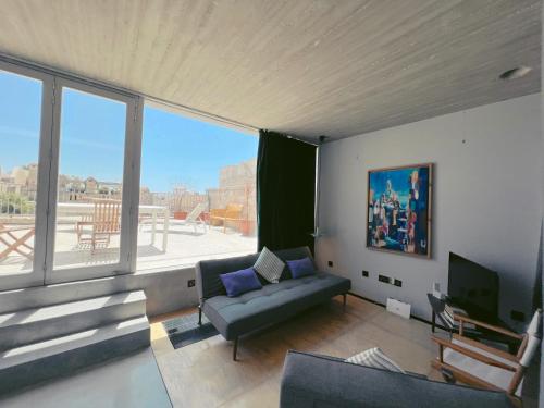 Una sala de estar con un sofá y una ventana grande. en CASA NOBILE APARTMENTS, en La Valeta
