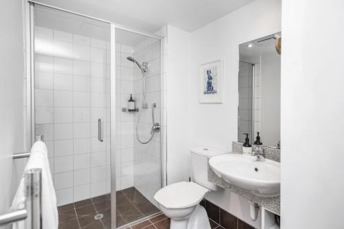 a white bathroom with a shower and a toilet and a sink at Cathedral Junction Apartments in Christchurch