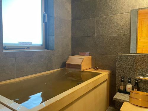 a bath tub filled with water in a bathroom at Hatagoya Jozankei Shoten-Adult Only in Sapporo