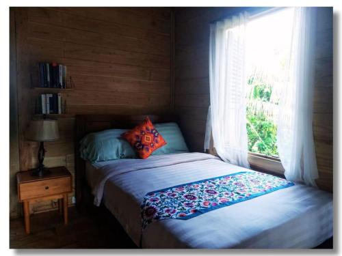 a small bedroom with a bed and a window at Jungle Haven Bali - Eco Lodge in Meliling