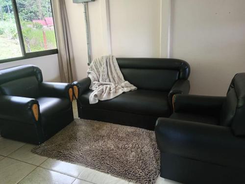 a living room with a black couch and two chairs at SanTab's Home in Colonia