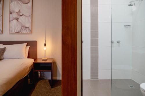 a bedroom with a bed and a glass shower at Mitchell On Main in Bairnsdale