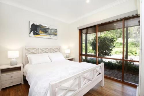 a white bedroom with a large bed and a window at Belaradah on Stefani Estate Winery in Healesville