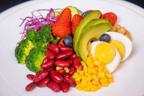 a plate of fruit and vegetables on a plate at Hilton Haikou Meilan - Beachfront Hotel in Haikou