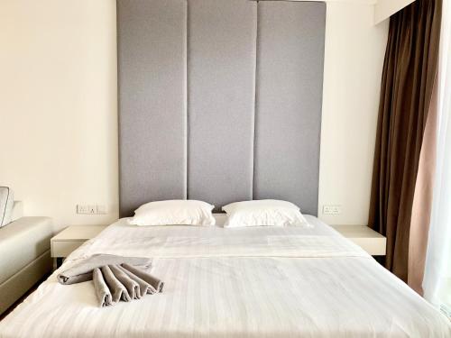 a bed with white sheets and a headboard in a room at Deco Home @ Aru Suites in Kota Kinabalu