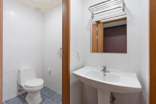 a white bathroom with a toilet and a sink at Namhae Season Hotel in Namhae