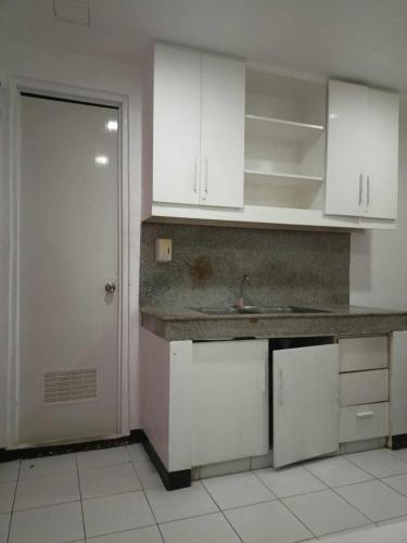 a kitchen with white cabinets and a sink and a door at WJV INN BASAK MANDAUE BRANCH in Mandaue City