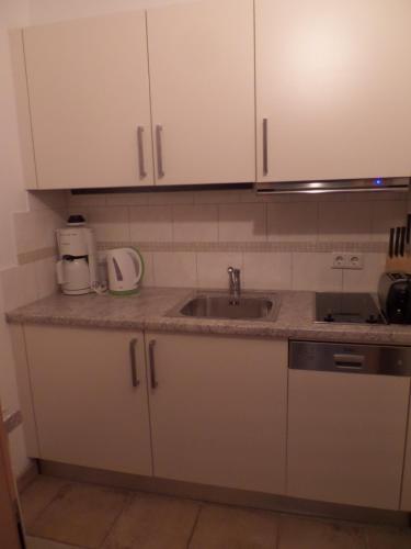 a kitchen with white cabinets and a sink at Forellenstube in Lofer