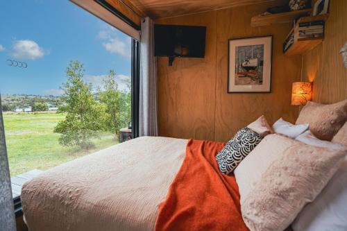 a bedroom with a bed and a large window at Tiny House at the Moorings in Dunalley