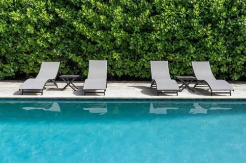 a group of lounge chairs next to a swimming pool at Villa Palma-Hollywood Beach - Winter & Spring Break Getaway! in Hollywood