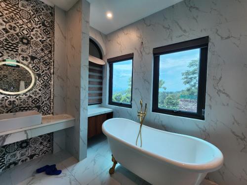 baño con bañera blanca y ventana en Mây Trắng Farmstay Villas Venuestay, en Ba Vì