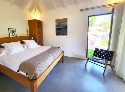 a bedroom with a bed and a window and a chair at Villa Coco Rock in Saint Barthelemy