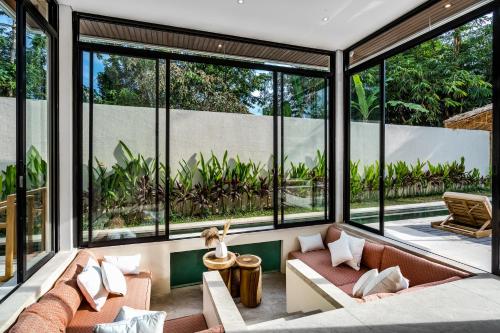 a living room with large windows and a couch at Villa Elma by BaliSuperHost in Ubud