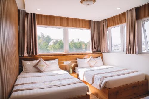 two beds in a room with two windows at Ánh Phương Hotel Đà Lạt in Da Lat