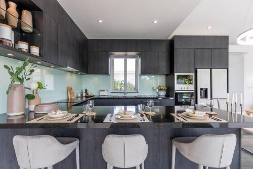 a kitchen with a large island with white chairs at Big & Stylish 5 Bed 4 Bath Private Garden Pool Villa at Thongson Bay Beach in Koh Samui 