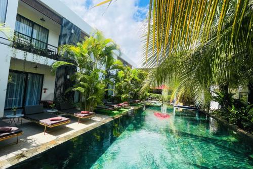 a swimming pool in a hotel with chairs and trees at Central Corner Suite in Siem Reap