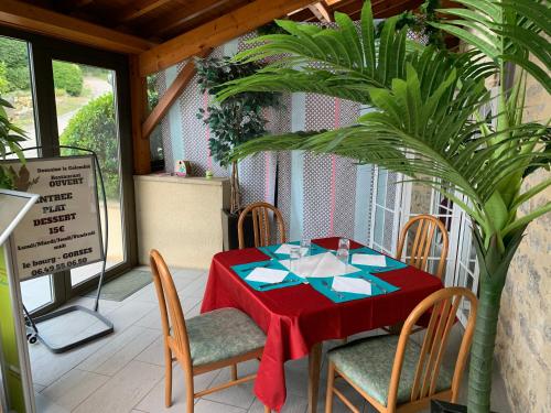 une table avec une nappe rouge et des chaises sur une terrasse couverte dans l'établissement Hotel Colombié, à Gorses