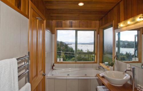 a bathroom with a tub and a sink and a window at Cliff Edge by the Sea in Paihia