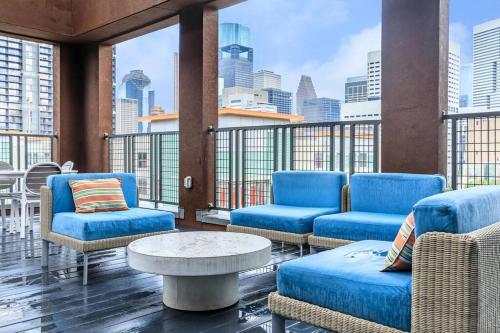 a balcony with blue chairs and a table and a city at Downtown Houston Gem: Parking Pool WiFi Sleeps 4 in Houston