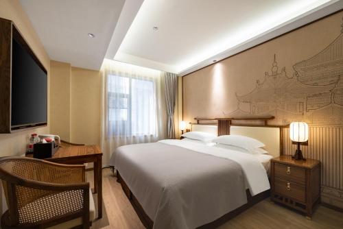 a bedroom with a large white bed and a television at Honglu Garden Hotel Xi'an Bell and Drum Tower Huimin Street Store in Xi'an