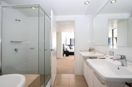 uma casa de banho com 2 lavatórios e uma cabina de duche em vidro. em Luxe High-rise with Al Fresco Dining & Ocean views em Gold Coast
