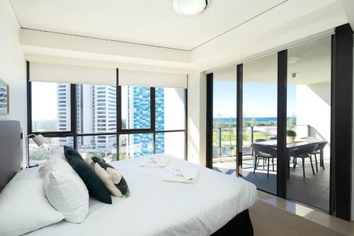 um quarto com uma cama branca e vista para uma mesa em Luxe High-rise with Al Fresco Dining & Ocean views em Gold Coast