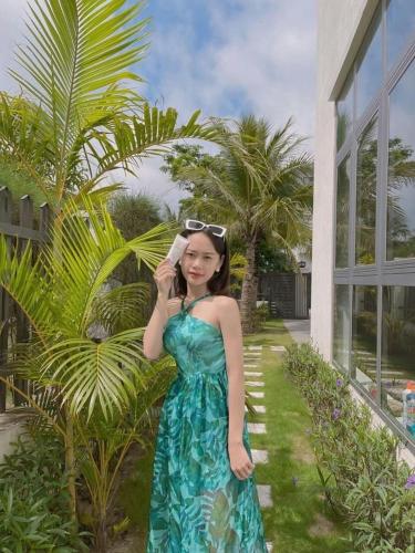 a woman in a dress talking on a cell phone at Sea Villa - FLC Sam Son in Sầm Sơn