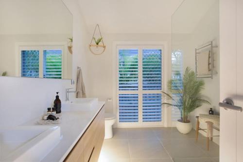ein weißes Bad mit 2 Waschbecken und einem Fenster in der Unterkunft Contemporary Coastal Luxury with an Outdoor Pool in Gold Coast