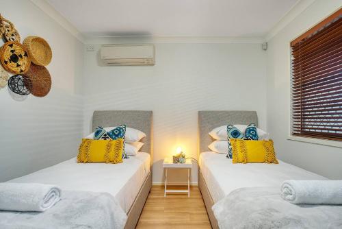 Cette chambre comprend 2 lits avec des oreillers jaunes et bleus. dans l'établissement 'Buzzing Surfers' Vibrant Indoor-outdoor Lifestyle, à Gold Coast