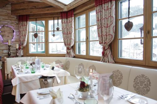 a dining room with two tables and windows at Familien- und Wellnesshotel Hanneshof in Kleinarl