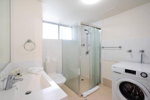a bathroom with a shower and a washing machine at Beautiful Burleigh - Contemporary Beachside Retreat in Gold Coast
