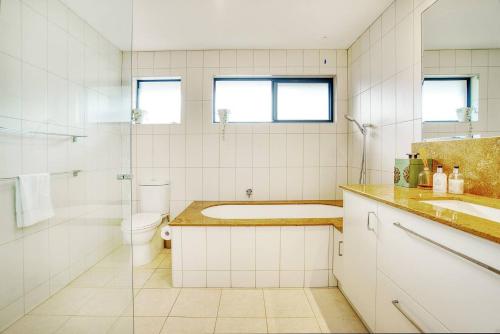 uma casa de banho com uma banheira, um WC e um lavatório. em Sunny Days Poolside at an Entertainer's Oasis em Gold Coast