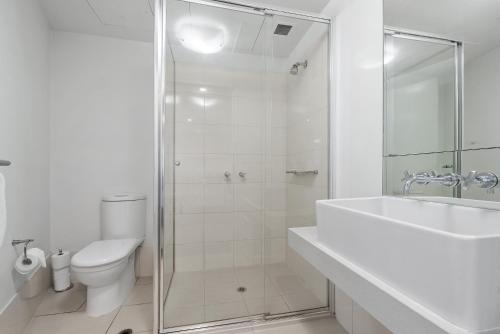 a white bathroom with a shower and a toilet at Resort Style Living Yarra Wharf in Melbourne