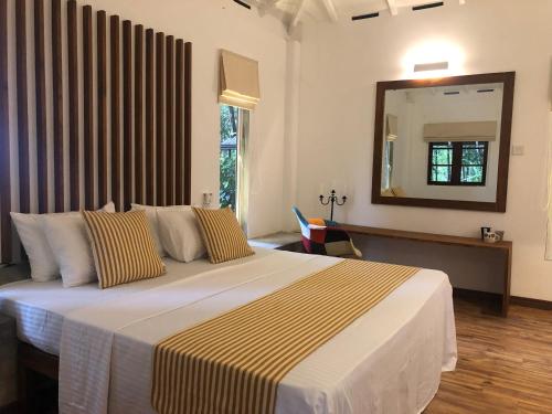 ein Schlafzimmer mit einem großen Bett und einem großen Spiegel in der Unterkunft River Garden Resort in Belihuloya