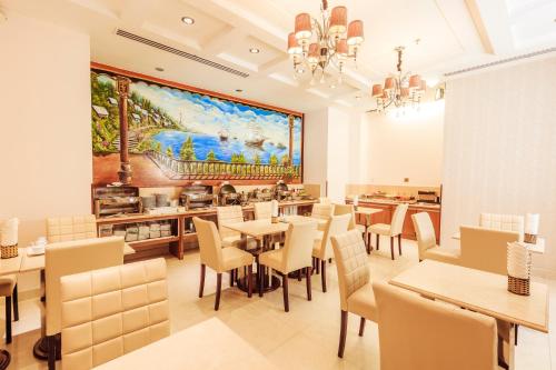 restauracja ze stołami i krzesłami oraz obrazem na ścianie w obiekcie Cap Town Hotel w Ho Chi Minh