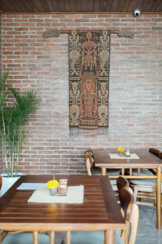 eine Backsteinmauer mit zwei Holztischen und Stühlen in der Unterkunft Santera Village in Canggu