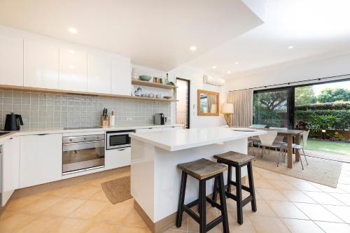 a kitchen with white cabinets and a table and chairs at Gwydir Court 1 in Forster